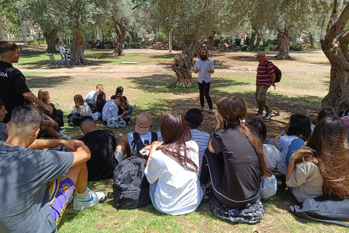 משתתפי סיור עומדים מול נוף עירוני של חיפה ומקשיבים להסבר על חיים משותפים בעיר המעורבת